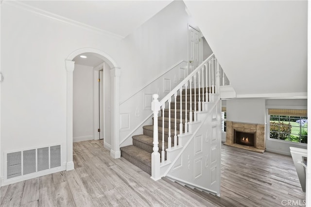 2720 Hilltop Dr Unit 58, Newport Beach, CA 92660 - staircase with wood finished floors, arched walkways, a lit fireplace, and crown molding