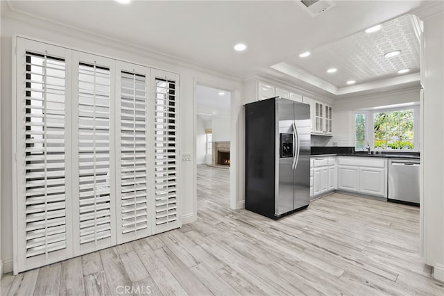 2720 Hilltop Dr Unit 58, Newport Beach, CA 92660 - kitchen with stainless steel appliances, ornamental molding, light wood-type flooring, dark countertops, and white cabinetry