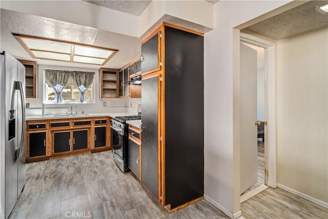 14811 Elizabeth Lake Rd, Lake Hughes, CA 93532 - kitchen with stainless steel appliances, under cabinet range hood, light countertops, brown cabinetry, and open shelves