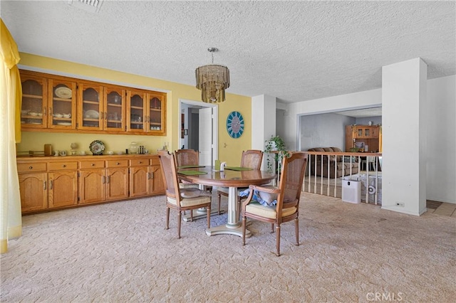 19428 Shasta Rd, Apple Valley, CA 92307 - dining area with light carpet, a textured ceiling, and a chandelier