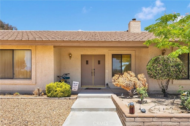 19428 Shasta Rd, Apple Valley, CA 92307 - property entrance with stucco siding, a chimney, and a tile roof