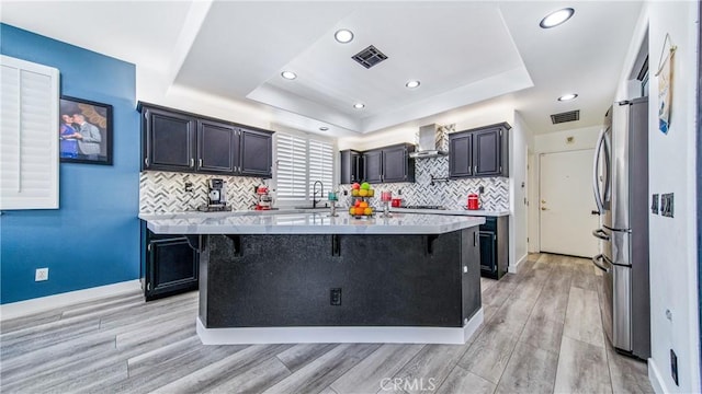 18223 Shannon Ridge Pl, Canyon Country, CA 91387 - kitchen featuring a raised ceiling, freestanding refrigerator, wall chimney range hood, light countertops, and a kitchen breakfast bar