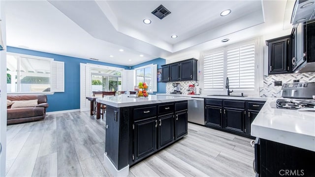 18223 Shannon Ridge Pl, Canyon Country, CA 91387 - kitchen featuring dark cabinets, stainless steel dishwasher, a tray ceiling, a center island, and light wood finished floors