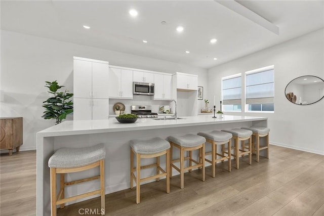 426 W Central Ave, Brea, CA 92821 - kitchen featuring stainless steel appliances, light wood-style floors, light countertops, white cabinetry, and a breakfast bar