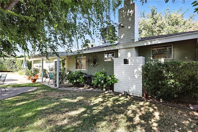 2997 June Ct, Merced, CA 95348 - view of side of home featuring a patio area, a chimney, and a lawn