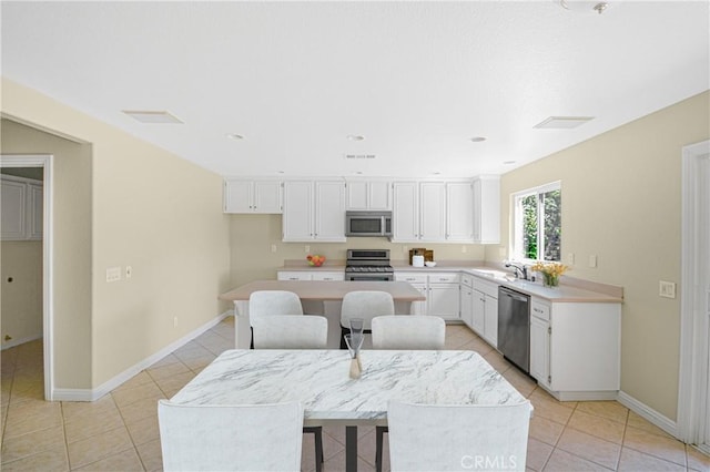 30526 Beryl Pl, Castaic, CA 91384 - kitchen featuring stainless steel appliances, light tile patterned floors, white cabinets, light countertops, and a kitchen island