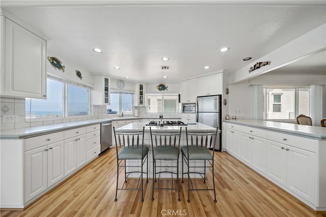 6536 Oceanview Dr Unit T, Carlsbad, CA 92011 - kitchen featuring stainless steel appliances, a breakfast bar area, light wood-style floors, tasteful backsplash, and recessed lighting