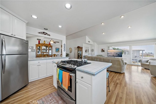 6536 Oceanview Dr Unit T, Carlsbad, CA 92011 - kitchen with appliances with stainless steel finishes, open floor plan, light wood-type flooring, tile counters, and vaulted ceiling