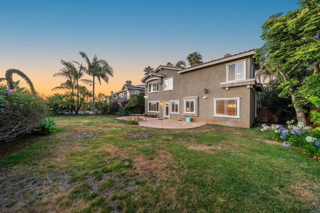 1033 Goldeneye, Carlsbad, CA 92011 - back of house at dusk with a patio area, a lawn, and stucco siding