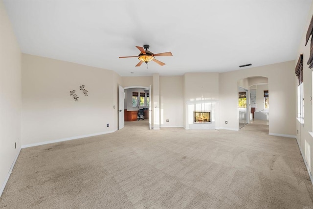 1033 Goldeneye, Carlsbad, CA 92011 - unfurnished living room featuring arched walkways, light colored carpet, a ceiling fan, and a glass covered fireplace