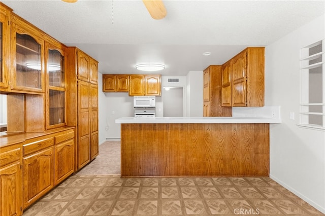 16257 Avalon Ave, Victorville, CA 92395 - kitchen featuring white microwave, light flooring, a peninsula, and brown cabinetry