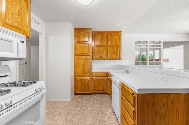 16257 Avalon Ave, Victorville, CA 92395 - kitchen with white appliances, brown cabinetry, a peninsula, light countertops, and light flooring