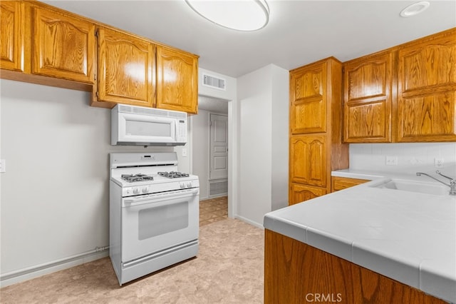 16257 Avalon Ave, Victorville, CA 92395 - kitchen featuring white appliances, tile counters, brown cabinetry, and light flooring