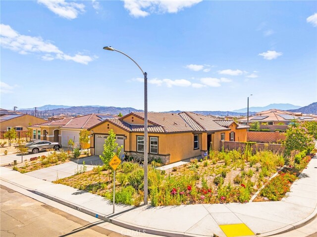 27108 Oncore Dr, Menifee, CA 92585 - view of front facade featuring a mountain view, a tile roof, an attached garage, driveway, and stucco siding