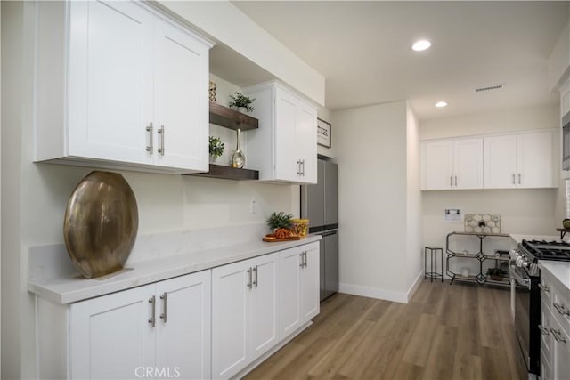 1610 Wandering Dr, Monterey Park, CA 91754 - kitchen featuring open shelves, gas range oven, freestanding refrigerator, light wood-style floors, and white cabinets