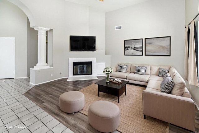 30602 Colina Verde St, Temecula, CA 92592 - living area featuring ornate columns, wood finished floors, arched walkways, a glass covered fireplace, and a towering ceiling