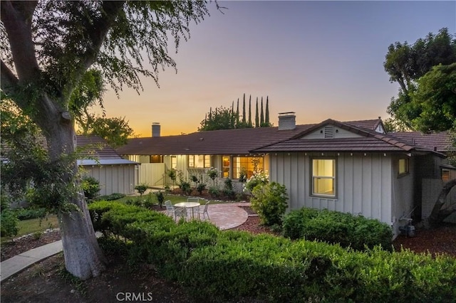 3131 E Cortez St, West Covina, CA 91791 - back of property at dusk featuring board and batten siding, a chimney, and a storage unit