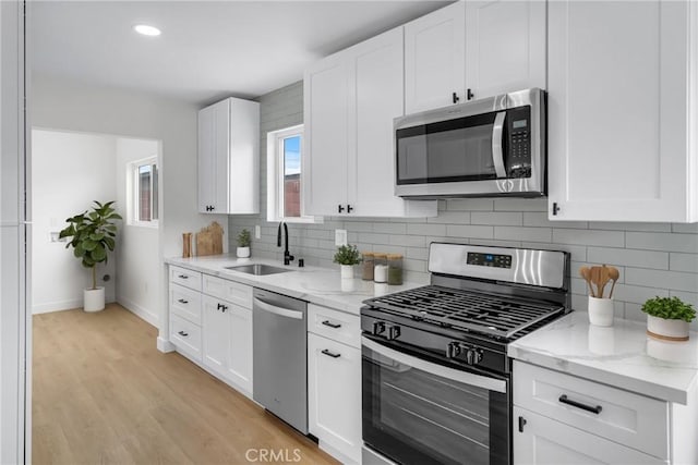 4713 Calada Ave, Pico Rivera, CA 90660 - kitchen featuring stainless steel appliances, decorative backsplash, light wood-type flooring, white cabinets, and light stone countertops