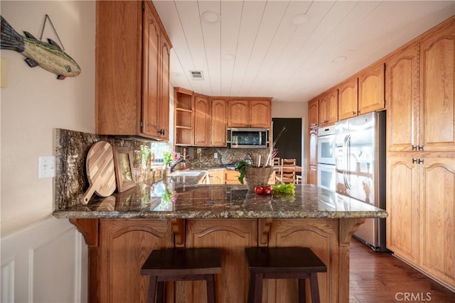 1244 St Anton Dr, Lake Arrowhead, CA 92352 - kitchen with appliances with stainless steel finishes, a peninsula, open shelves, dark wood-type flooring, and tasteful backsplash