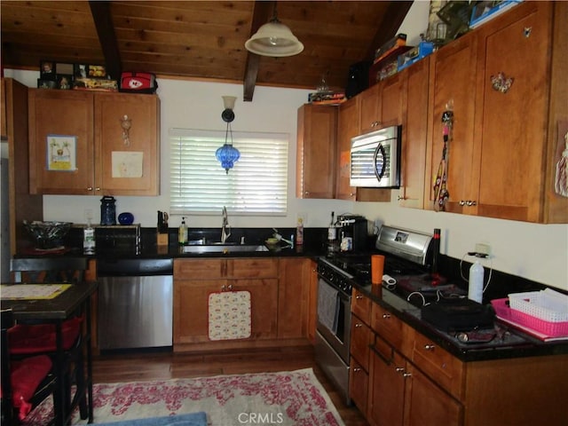 2493 Palo Alto Way, Running Springs, CA 92382 - kitchen with stainless steel appliances, brown cabinets, wood finished floors, dark countertops, and a wooden ceiling with exposed beams