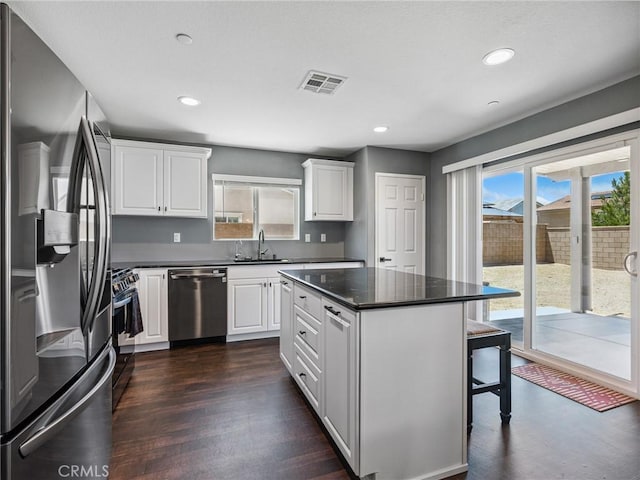 11760 Espola Pl, Victorville, CA 92392 - kitchen featuring stainless steel appliances, dark countertops, white cabinets, a kitchen bar, and recessed lighting