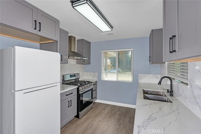 2246 Beachwood Dr, Merced, CA 95348 - kitchen with freestanding refrigerator, wall chimney range hood, gas stove, gray cabinets, and tasteful backsplash
