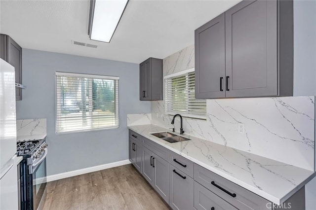 2246 Beachwood Dr, Merced, CA 95348 - kitchen featuring gas range, backsplash, plenty of natural light, and light wood-type flooring