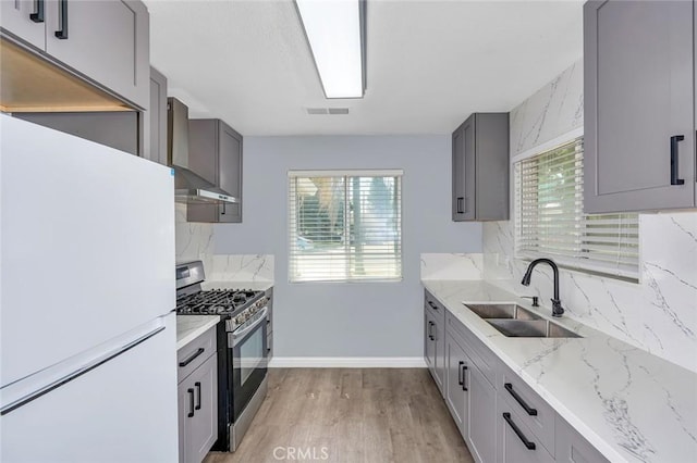 2246 Beachwood Dr, Merced, CA 95348 - kitchen with freestanding refrigerator, stainless steel range with gas cooktop, decorative backsplash, light wood-style floors, and plenty of natural light