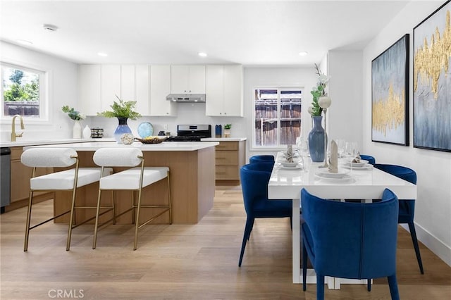 1851 S San Antonio Ave, Pomona, CA 91766 - kitchen with under cabinet range hood, stainless steel range, a kitchen island, light countertops, and a breakfast bar area