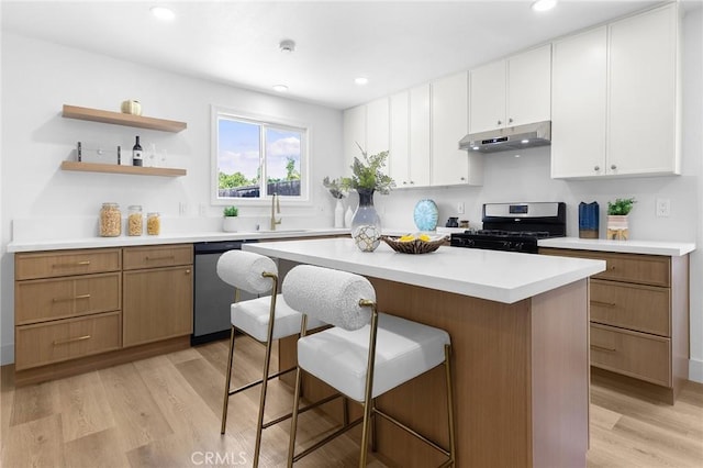 1851 S San Antonio Ave, Pomona, CA 91766 - kitchen with gas stove, under cabinet range hood, dishwasher, a breakfast bar area, and a center island
