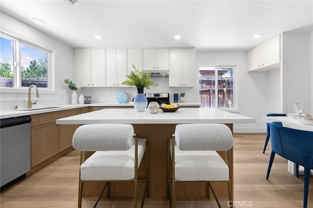 1851 S San Antonio Ave, Pomona, CA 91766 - kitchen featuring stainless steel dishwasher, light countertops, a breakfast bar area, a center island, and white cabinets