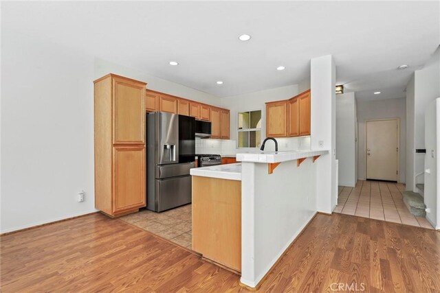 27664 Cordovan Dr, Canyon Country, CA 91351 - kitchen with appliances with stainless steel finishes, a peninsula, light wood-style floors, recessed lighting, and a kitchen breakfast bar