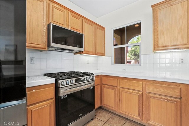 27664 Cordovan Dr, Canyon Country, CA 91351 - kitchen with stainless steel appliances, tile counters, decorative backsplash, and light tile patterned floors