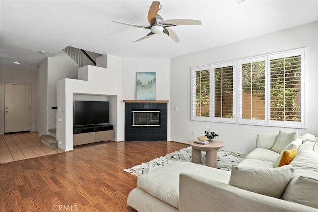 27664 Cordovan Dr, Canyon Country, CA 91351 - living room featuring ceiling fan, wood finished floors, a tiled fireplace, and stairs