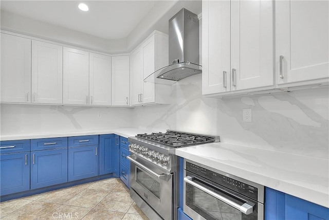 12790 Golden Leaf Dr, Rancho Cucamonga, CA 91739 - kitchen with wall chimney exhaust hood, appliances with stainless steel finishes, blue cabinetry, white cabinetry, and recessed lighting