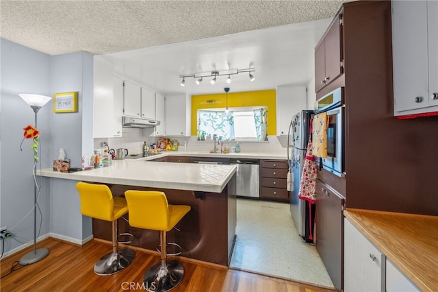 5110 E Atherton St Unit 57, Long Beach, CA 90815 - kitchen featuring appliances with stainless steel finishes, under cabinet range hood, a peninsula, tasteful backsplash, and a breakfast bar