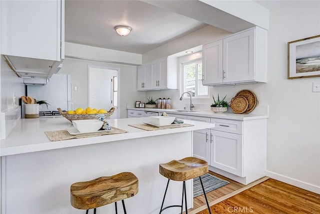 426 S Broadway, Redondo Beach, CA 90277 - kitchen with a peninsula, a kitchen breakfast bar, white cabinets, light countertops, and freestanding refrigerator