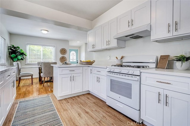 426 S Broadway, Redondo Beach, CA 90277 - kitchen with white range with gas stovetop, under cabinet range hood, light wood-type flooring, a peninsula, and light countertops