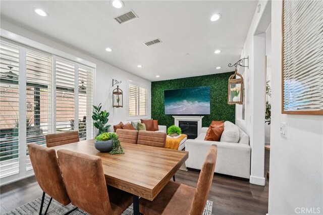 12400 Sarah Ct, El Monte, CA 91732 - dining space featuring an accent wall, dark wood-style flooring, recessed lighting, and a glass covered fireplace