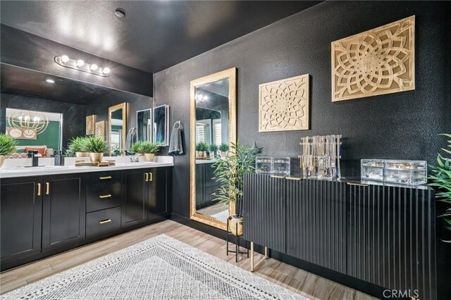 12400 Sarah Ct, El Monte, CA 91732 - bathroom featuring a textured wall, wood finished floors, double vanity, and a chandelier