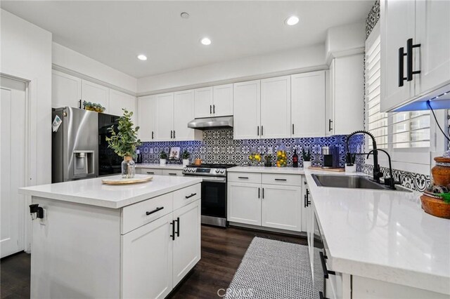 12400 Sarah Ct, El Monte, CA 91732 - kitchen with appliances with stainless steel finishes, under cabinet range hood, tasteful backsplash, dark wood finished floors, and light countertops