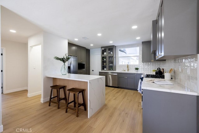 7830 Fairchild Ave, Winnetka, CA 91306 - kitchen with stainless steel appliances, a peninsula, light wood-style floors, decorative backsplash, and recessed lighting