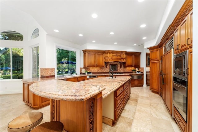 45200 Oak Manor Ct, Temecula, CA 92590 - kitchen with stainless steel appliances, backsplash, a kitchen bar, recessed lighting, and light stone counters