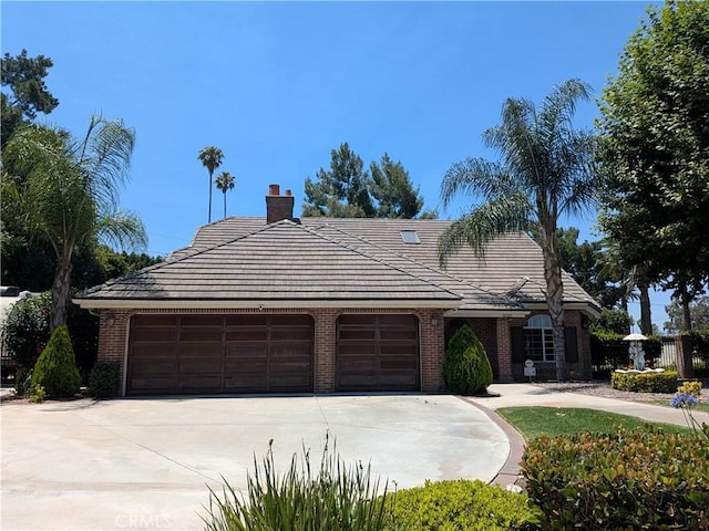 2622 Chauncy Pl, Riverside, CA 92506 - view of front of property with an attached garage, driveway, brick siding, a tile roof, and a chimney