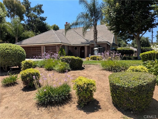 2622 Chauncy Pl, Riverside, CA 92506 - view of front facade featuring a tiled roof, a garage, brick siding, and a chimney