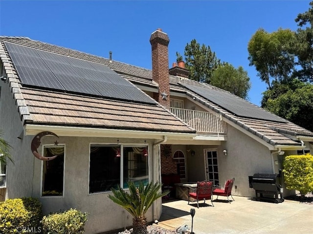 2622 Chauncy Pl, Riverside, CA 92506 - rear view of property featuring a balcony, roof mounted solar panels, stucco siding, a patio area, and a chimney