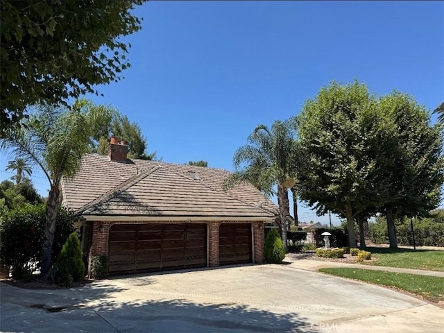 2622 Chauncy Pl, Riverside, CA 92506 - view of front facade featuring an attached garage, brick siding, driveway, and a chimney