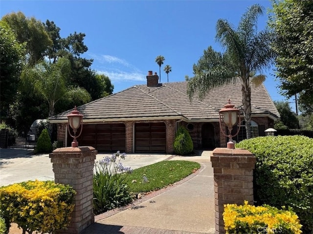 2622 Chauncy Pl, Riverside, CA 92506 - view of front of home featuring a garage, concrete driveway, a chimney, and brick siding