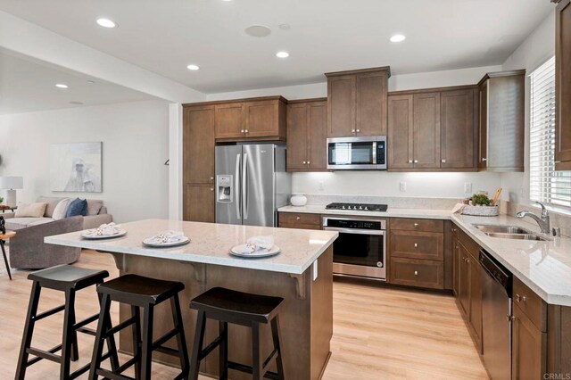 2333 Verano Way, Vista, CA 92081 - kitchen featuring stainless steel appliances, a breakfast bar area, light stone countertops, light wood-style floors, and recessed lighting