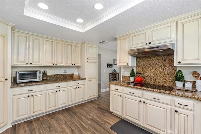9292 Garden St, Rancho Cucamonga, CA 91701 - kitchen featuring cream cabinets, under cabinet range hood, black electric cooktop, dark wood-type flooring, and backsplash